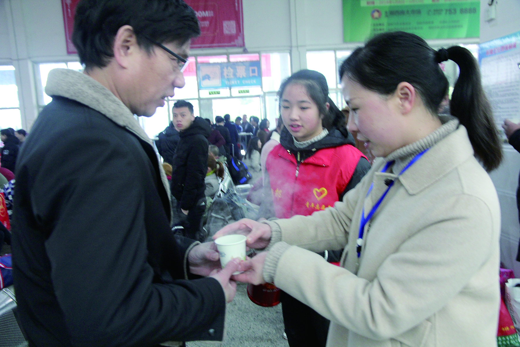 母女服務(wù)春運(yùn) 2月13日，記者在新邵分公司汽車站看到，該分公司安全科副科長李喜梅與其在新邵一中初中部1701班就讀女兒劉嘉怡在車站擔(dān)當(dāng)志愿者。李喜梅在候車室耐心為旅客釋疑解惑，劉嘉怡為旅客遞上一杯杯熱茶，有時母女也相互合作，其樂融融。 祖冠 攝影報道